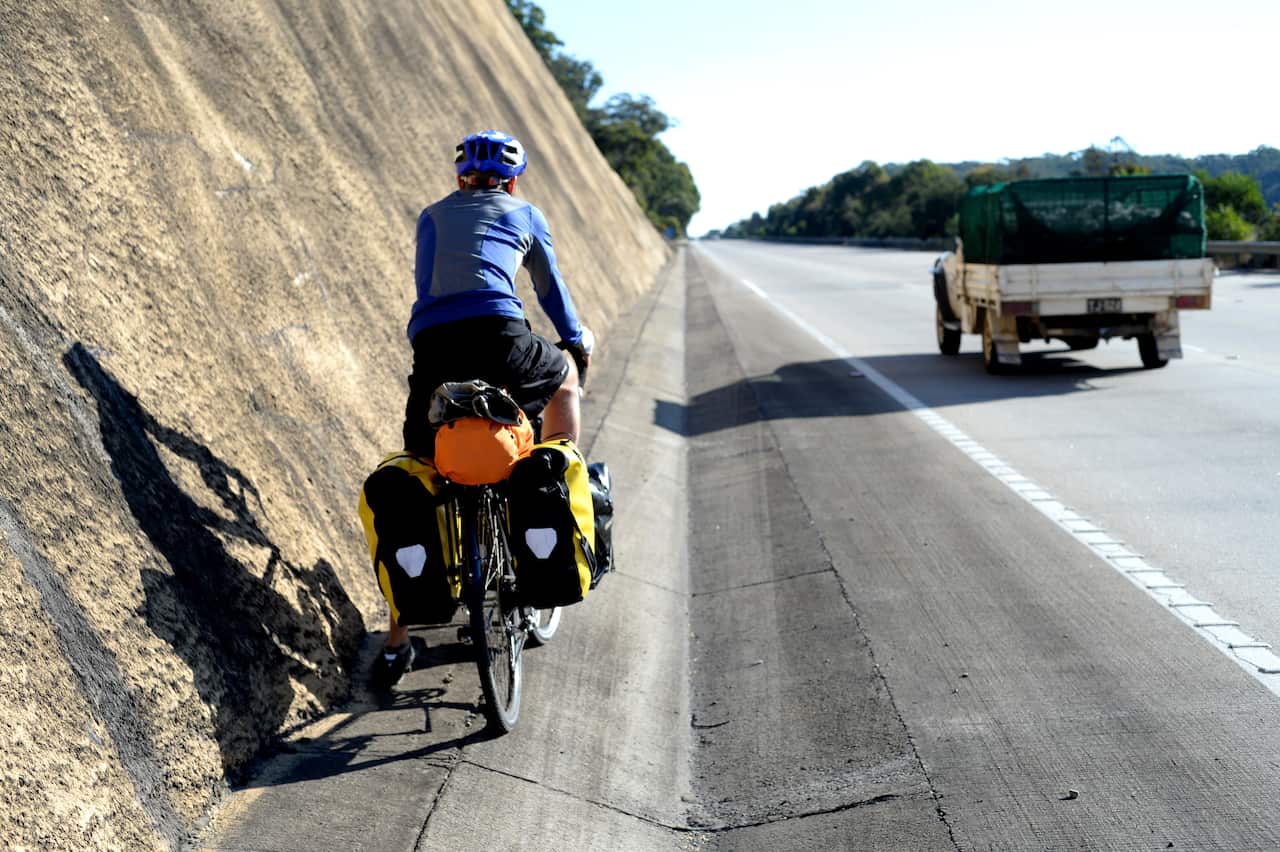 A cyclist rides along a highway.