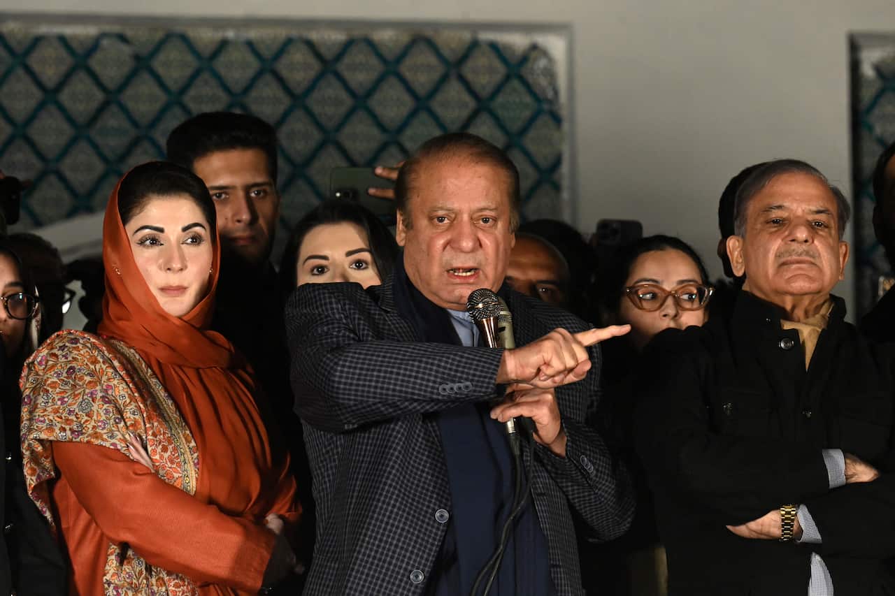 A man speaking into a microphone surrounded by other people.