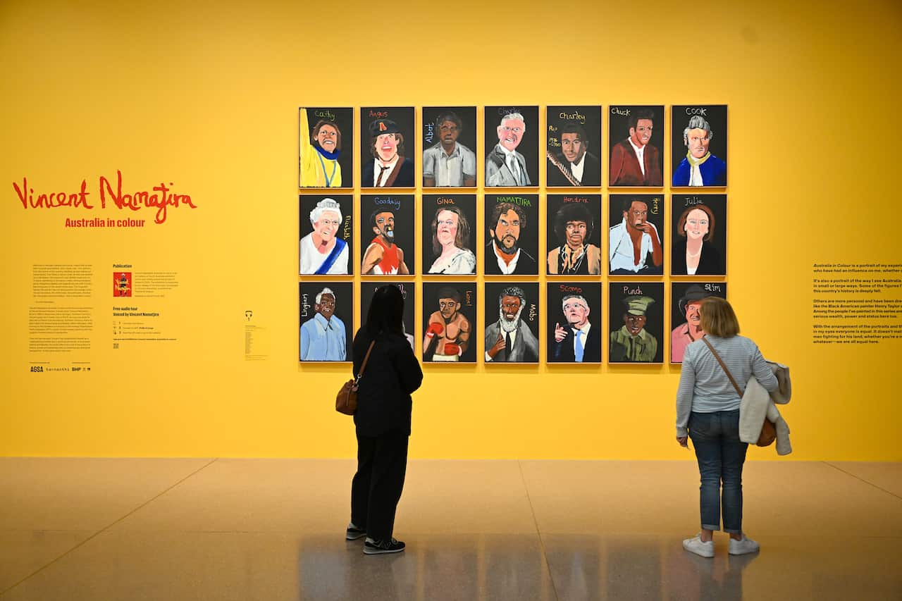 Two people look at Vincent Namatjira's Australia In Colour portrait series