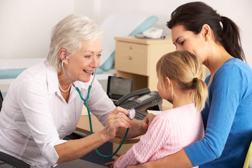 A doctor checks a young patient's chest with a stethoscope. 