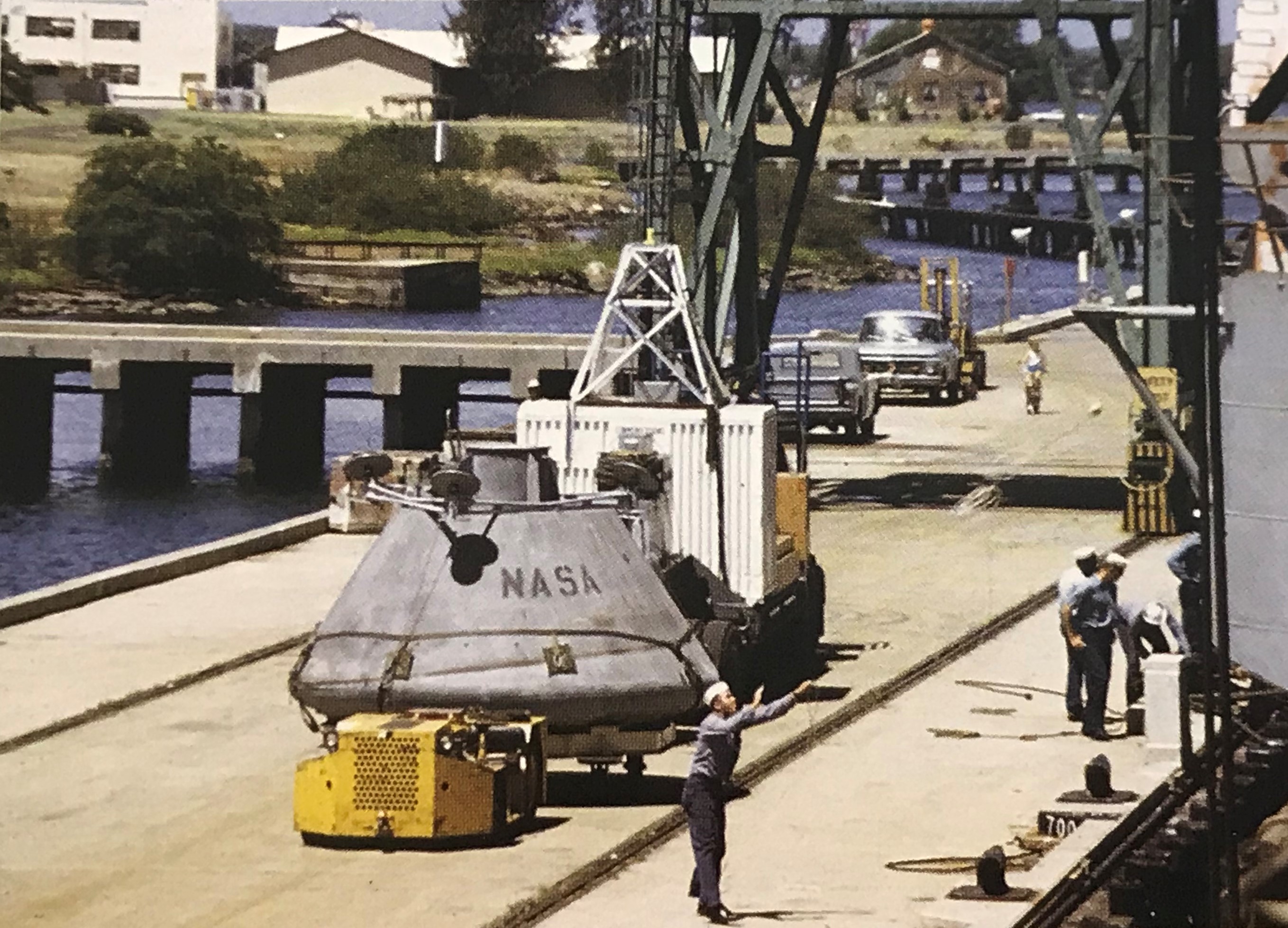 Workers in Pearl Harbor, Hawaii, prepare to lift a boilerplate Apollo Command Module onto the U.S.S. Hornet for splashdown and recovery rehearsals