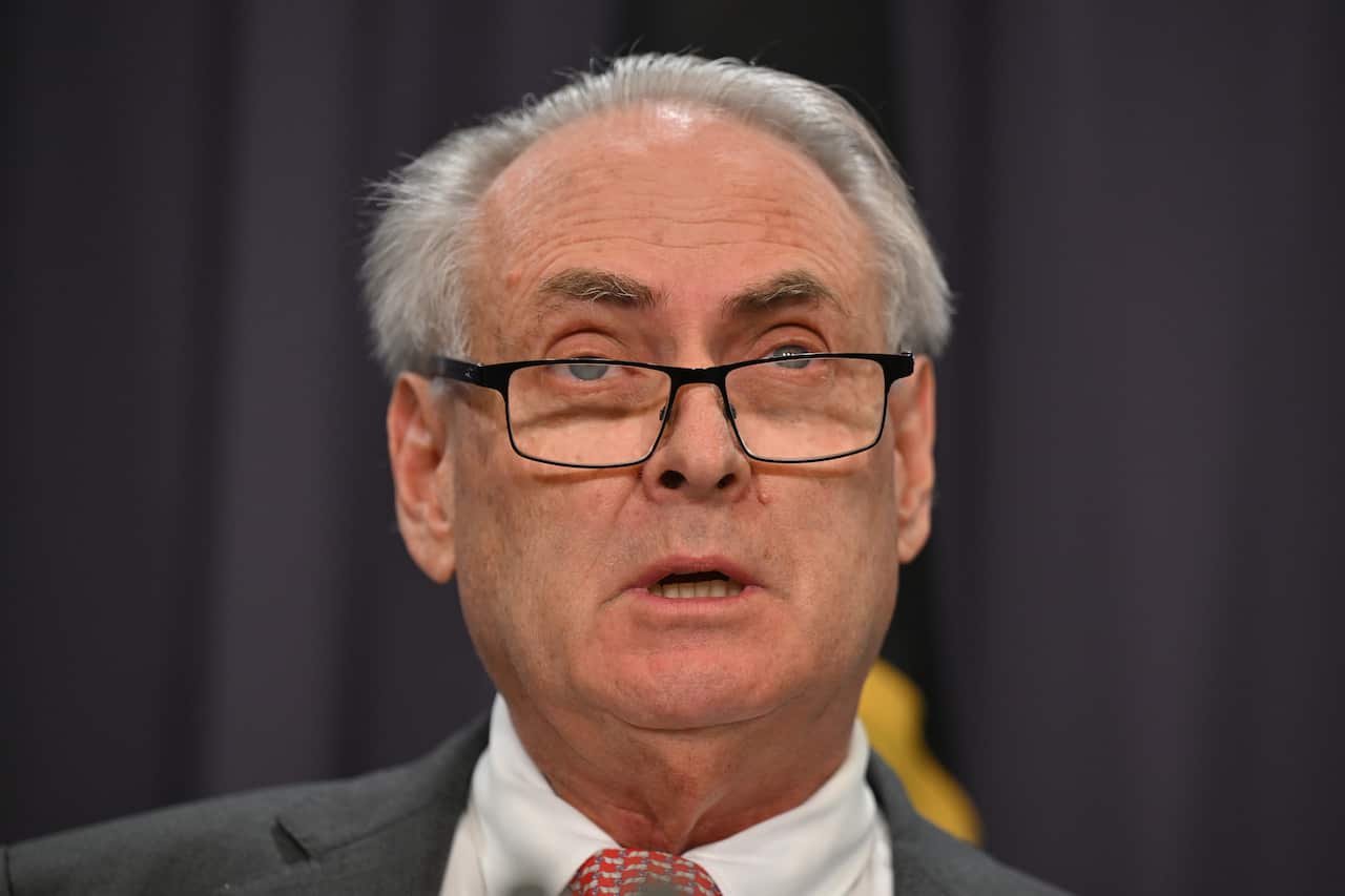 A man, wearing a suit, tie and glasses, is speaking.