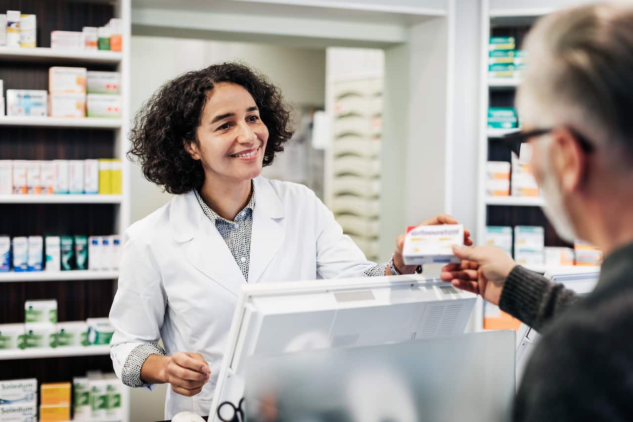 A pharmacist handing a customer medicine.