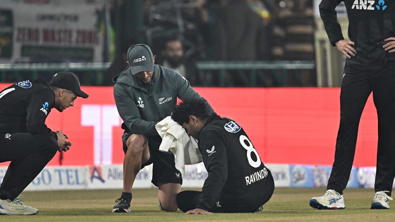 New Zealand's Rachin Ravindra (C) receives medical attention after being hit on the head by the ball during the Tri-Nation's first one-day international cricket match between Pakistan and New Zealand at the Gaddafi Stadium in Lahore on February 8, 2025. (Photo by Farooq NAEEM / AFP)