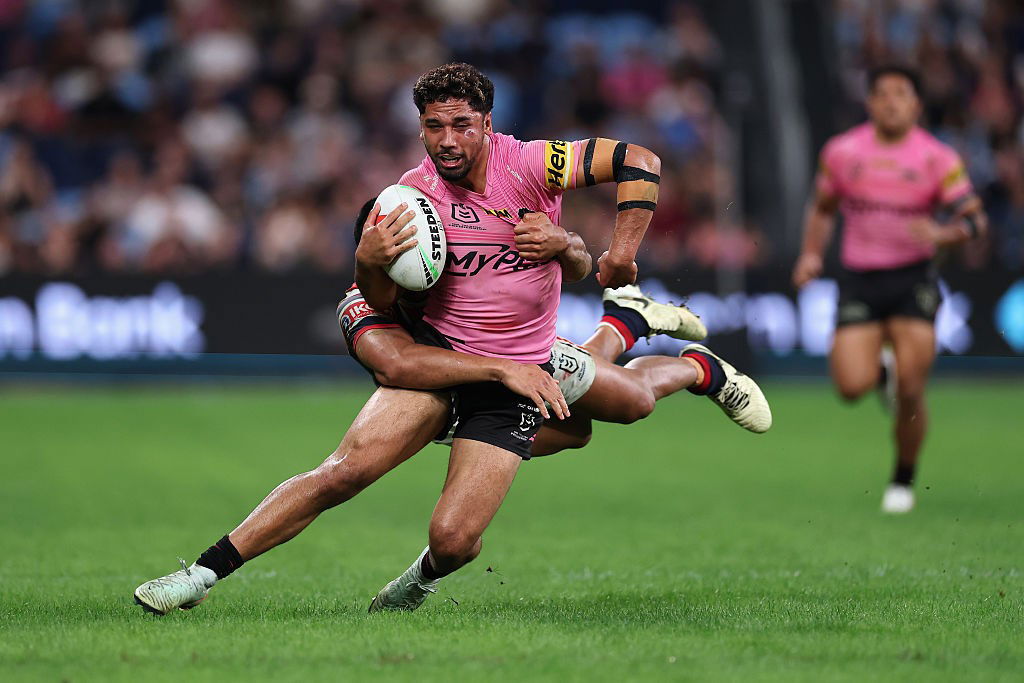 Izack Tago is tackled by a Roosters player.