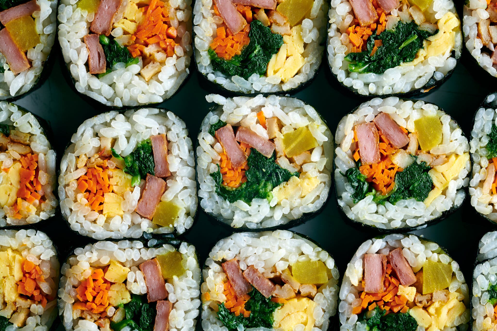 Several kimbap rolls sit on a surface.