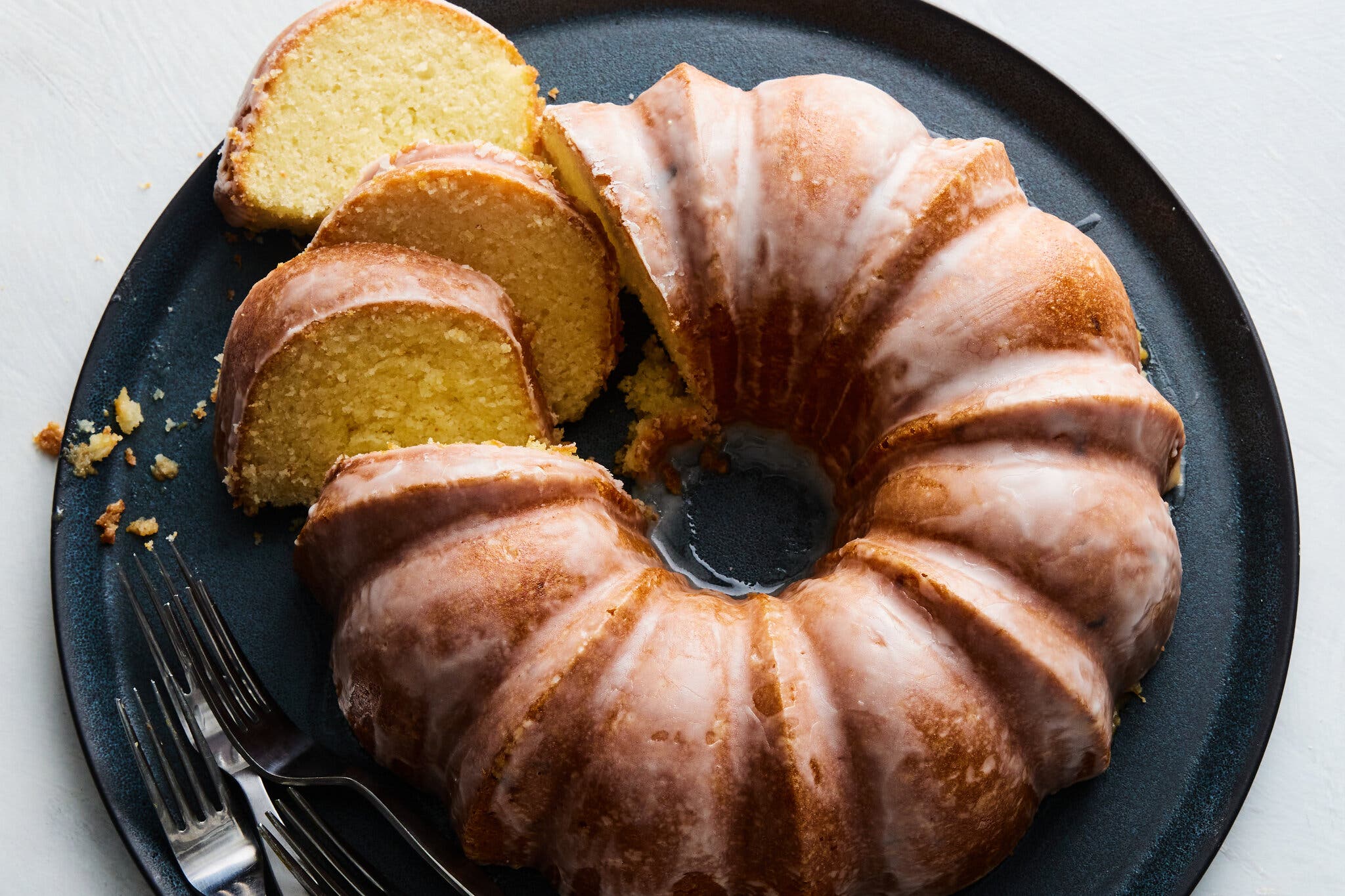 An overhead image of a partly sliced glazed Bundt cake on a black plate.