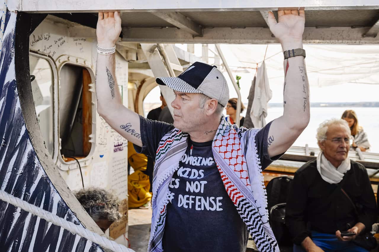 A man holds onto the side of a ship