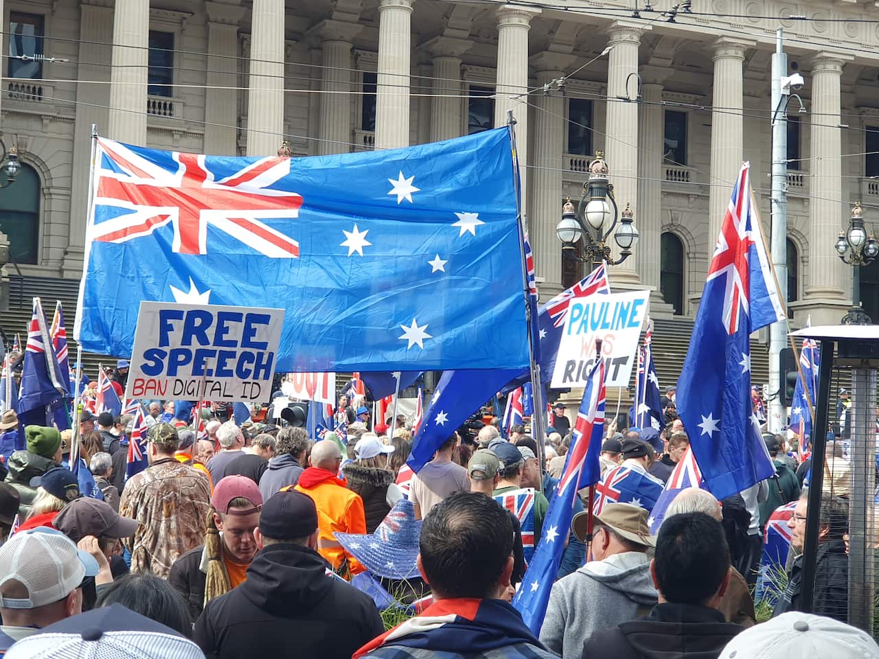 A crowd of people with a large Australian flag being held above their heads