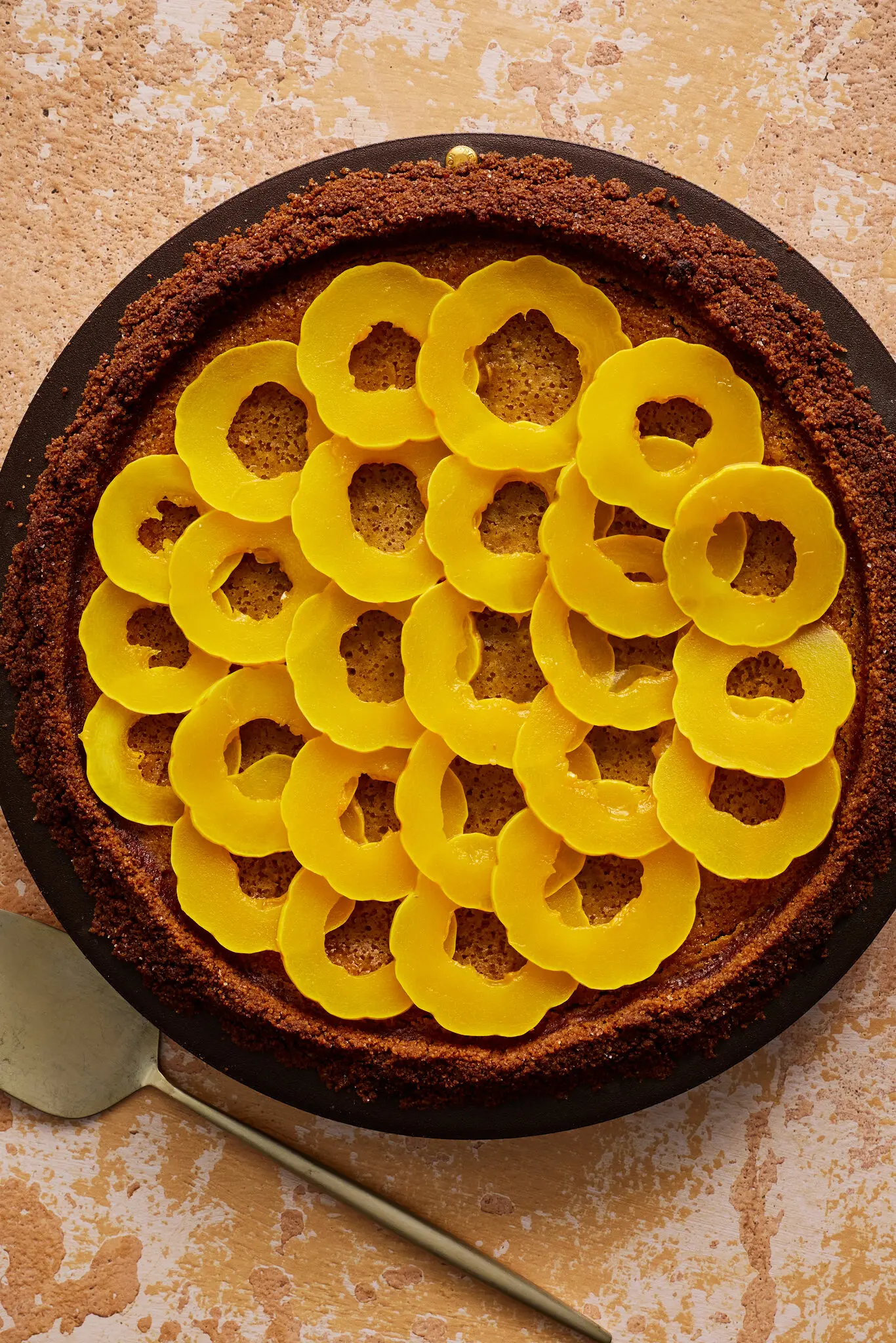 An overhead shot of a pie with a crumbly brown crust, topped with layered rings of delicata squash.