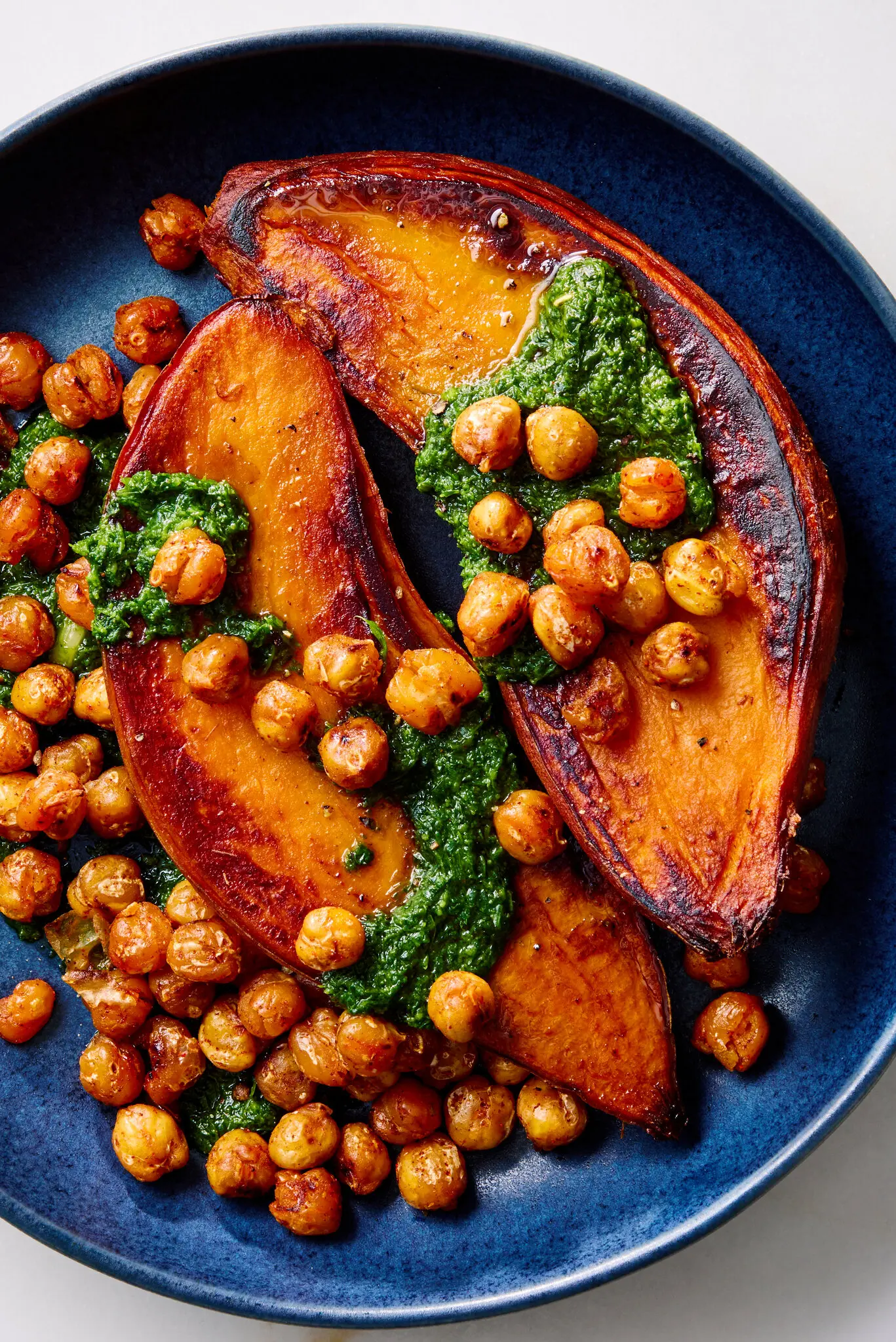 Two slices of sweet potatoes are bathed in charmoula and roasted chickpeas.
