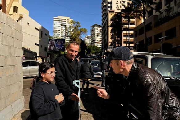 David Crowe (right) talks with Fatima and her grandfather, Ahmad Sweidan, in front of the Ramada Plaza hotel in Beirut after an Israeli drone strike on the building. 