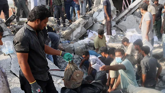 A man hold a children’s backpack as rescue workers and residents search through the rubble in the aftermath of an Israeli-US strike on what Iranian officials said was on a girls’ elementary school in Minab, Iran.