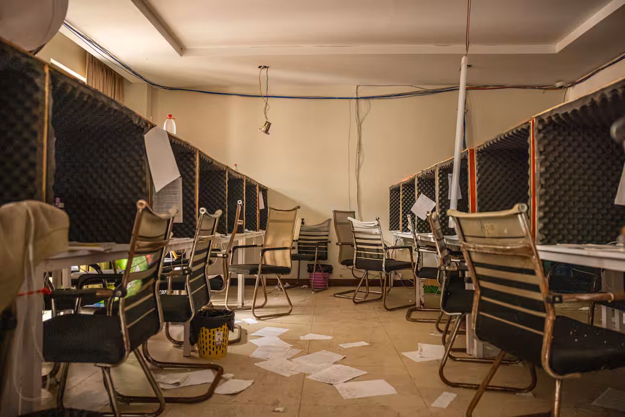 Tables and chairs and papers scattered on the floor under an outdoor tent