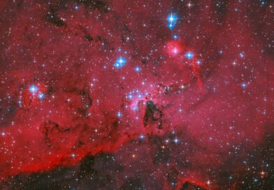 NASA’s Hubble Captures Crimson Cloud Sparkling with White, Blue Stars
