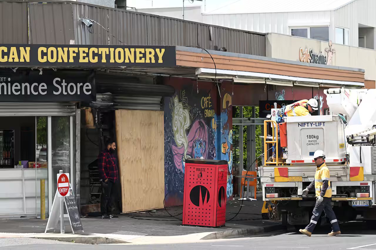 A convenience store that has been set on fire on an urban street.