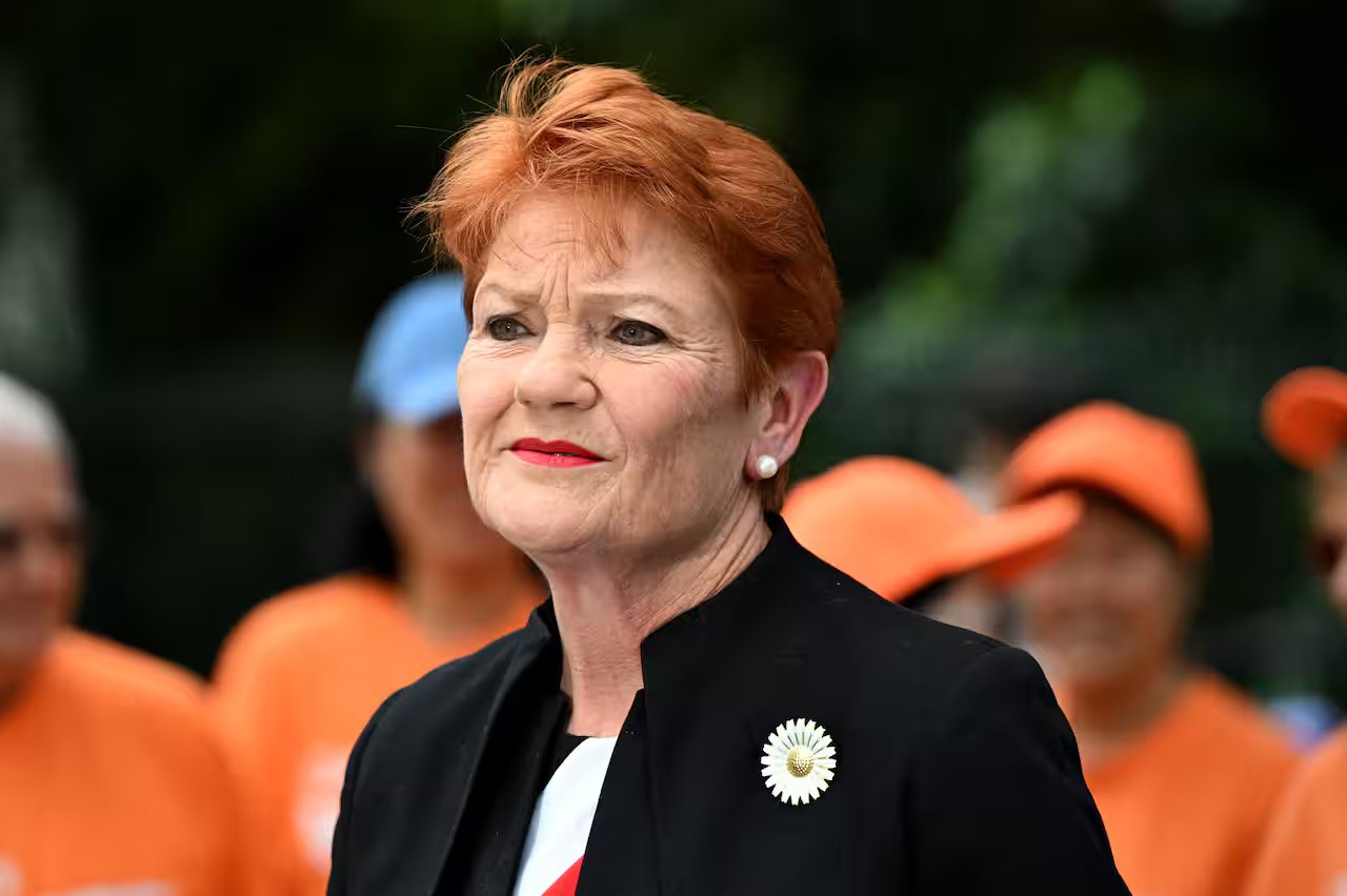 A woman with red short hair in a dark blazer