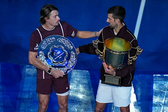 Alex de Minaur congratulates Beijing champion Novak Djokovic after retiring from their final with an injury.