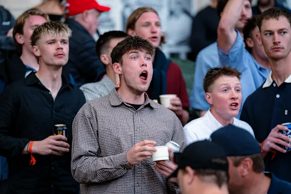 Spectators watch on as the greyhounds race.